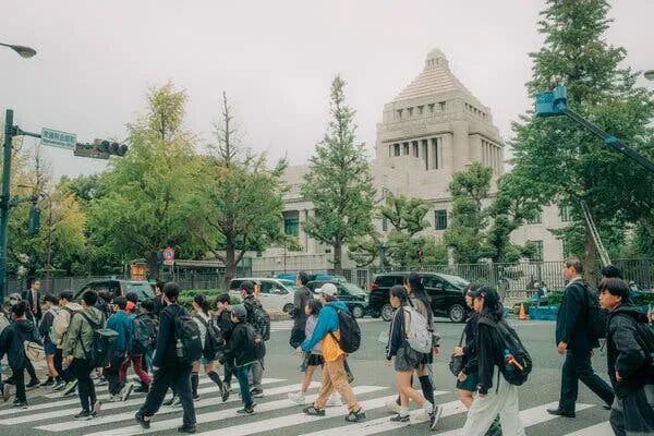 Students crossing the road in front of an elegant building.