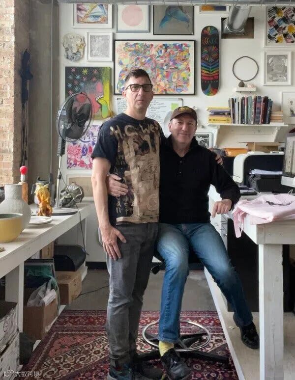 The author and his partner embrace each other while surrounded by colorful art.