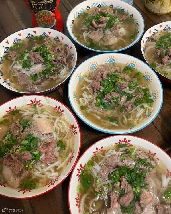 A table with six bowls of beef pho.