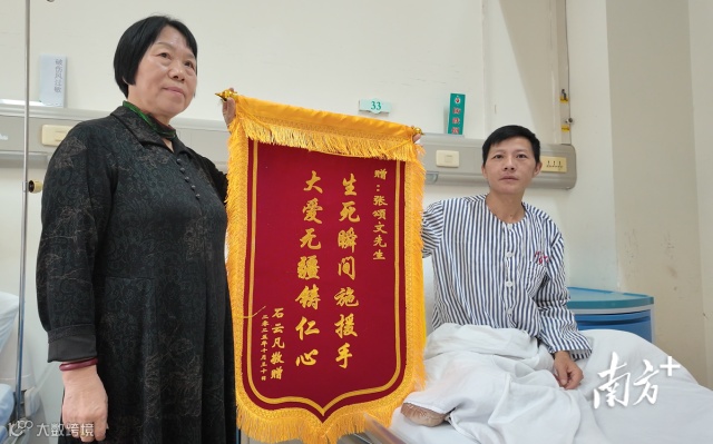 石先生和他妈妈展示着准备的锦旗。 南方+ 曹伟峰 拍摄