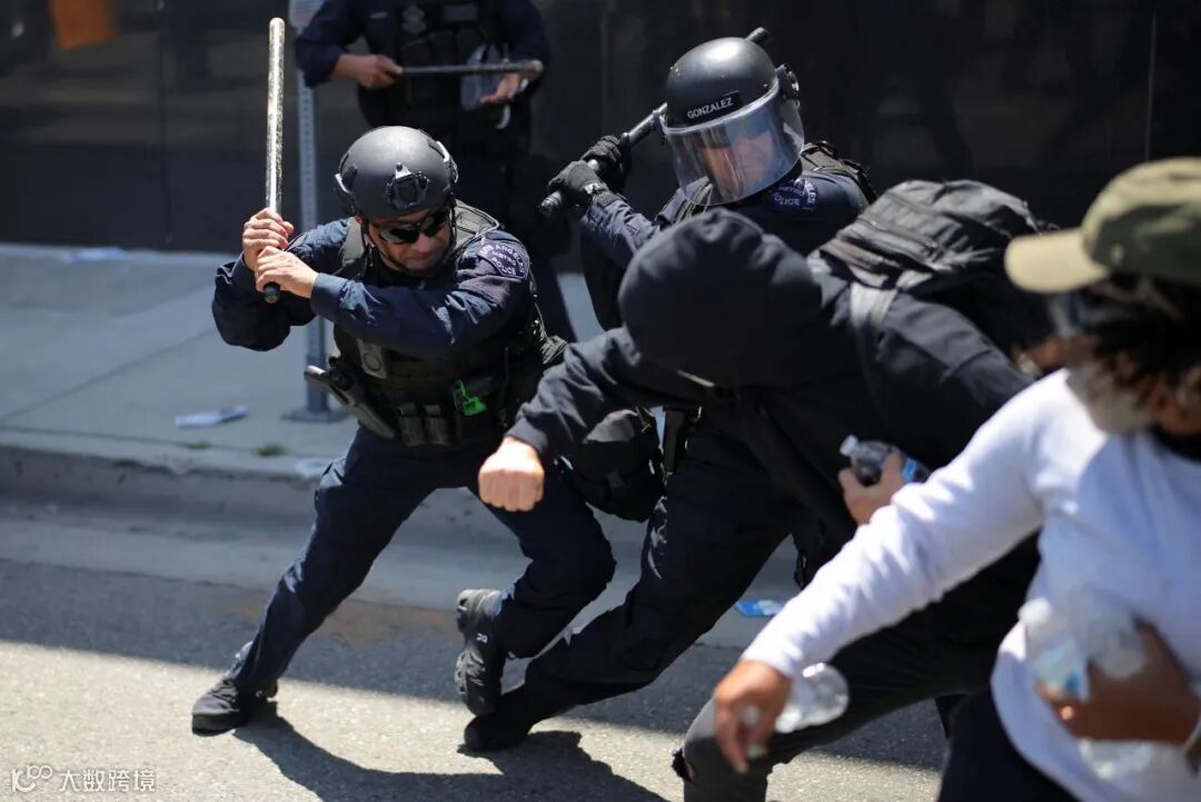 Los Angeles Metro Police officers swing their batons at demonstrators during a protest against federal immigration sweeps in Los Angeles on Sunday.