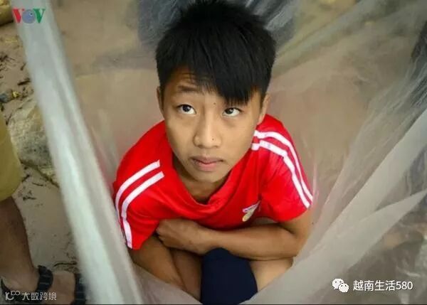 上学时,为避免弄湿衣服,越南人将小孩装进塑料袋拖着过河