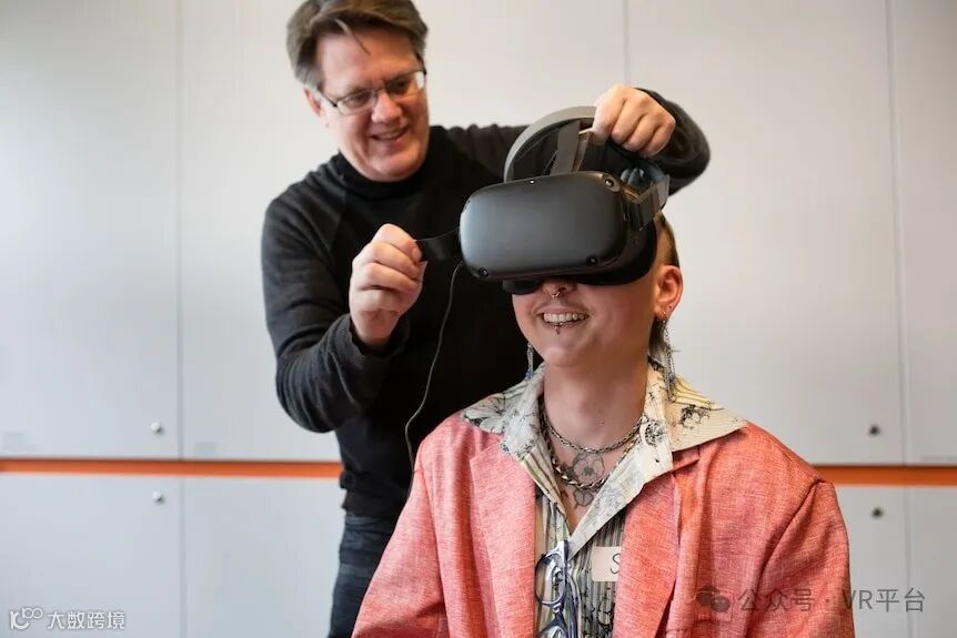 一名男子用左手将 VR 头戴设备向上抬起，帮助一名年轻男子调整 VR 头戴设备。