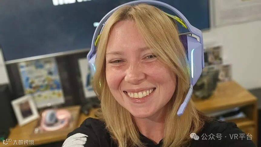 一位面带微笑的金发女子，戴着一副游戏耳机。