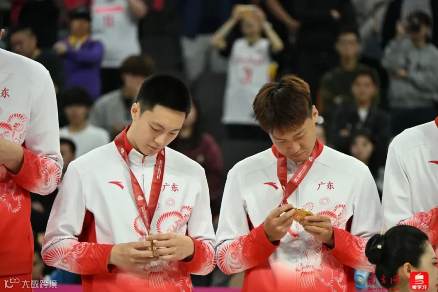 11月12日，广东队勇夺十五运会男篮成年组冠军。颁奖仪式上，胡明轩（左）与赵睿（右）仔细端详奖牌。这是广东男篮时隔12年再次获得该项目金牌。