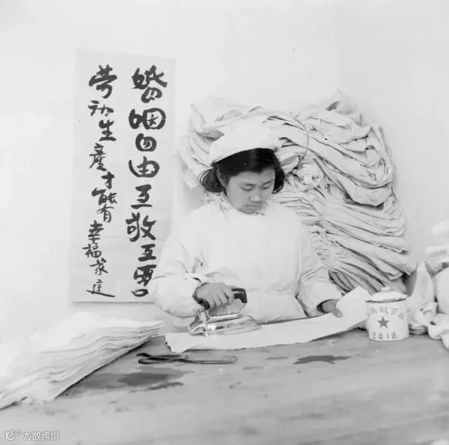 A slogan at a clothing factory reads, “Freedom of marriage, respect and love each other; only work and produce could create a happy family,” Beijing, 1953.