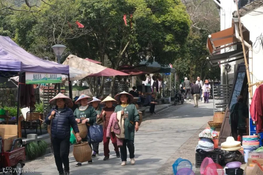 Tea pickers walk through Meijiawu with bamboo baskets.