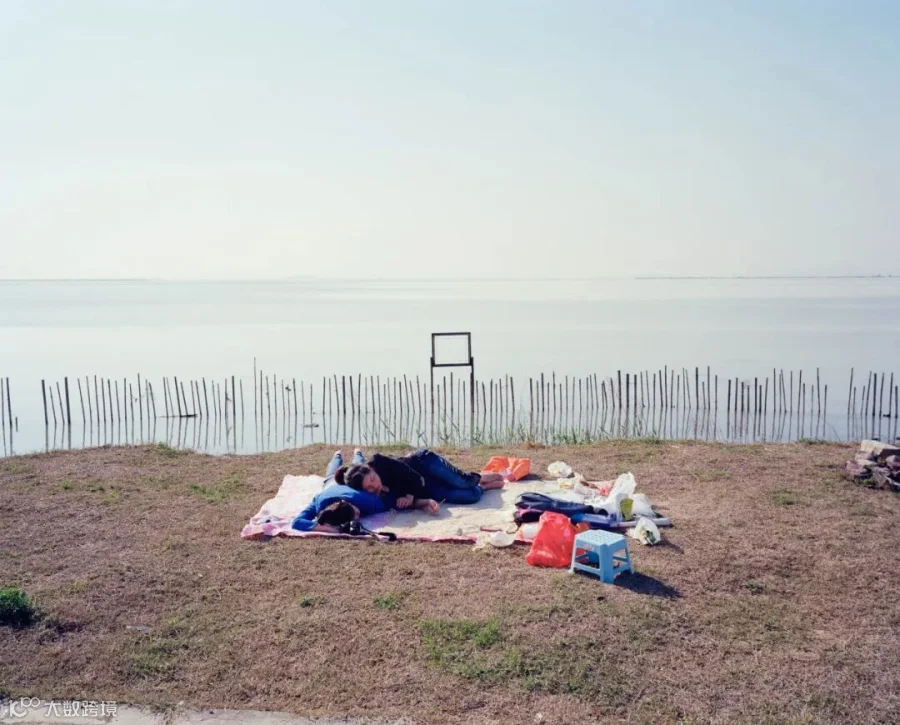 Two people enjoy a picnic on the grass by Lake Tai in Suzhou, Jiangsu province, 2013. Courtesy of Chen Liang