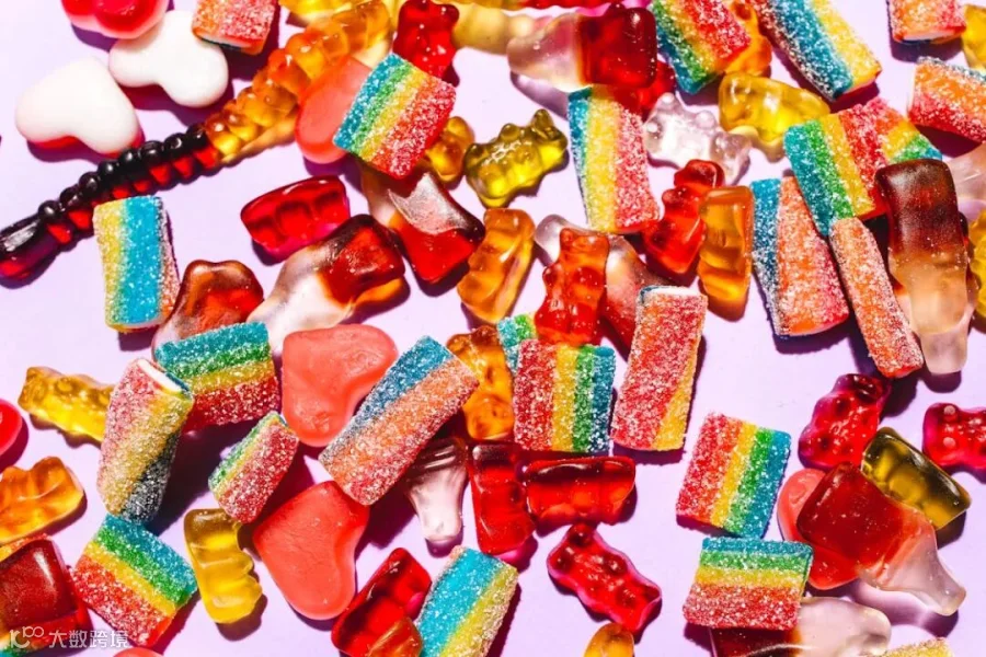Free Colorful mix of gummy candies including bears and rainbow strips on a vibrant purple backdrop. Stock Photo