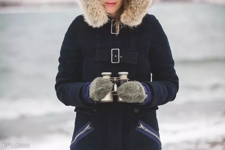 戴双筒望远镜的冬天女人
