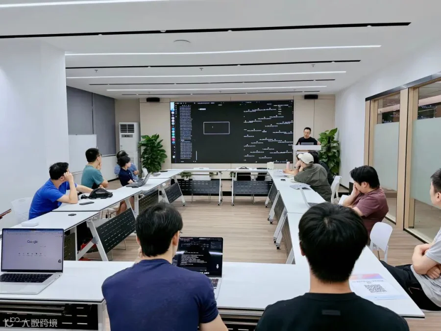 在技术分享现场，大家围坐一圈，边听边记，屏幕上的代码与讨论内容成为全场焦点。
