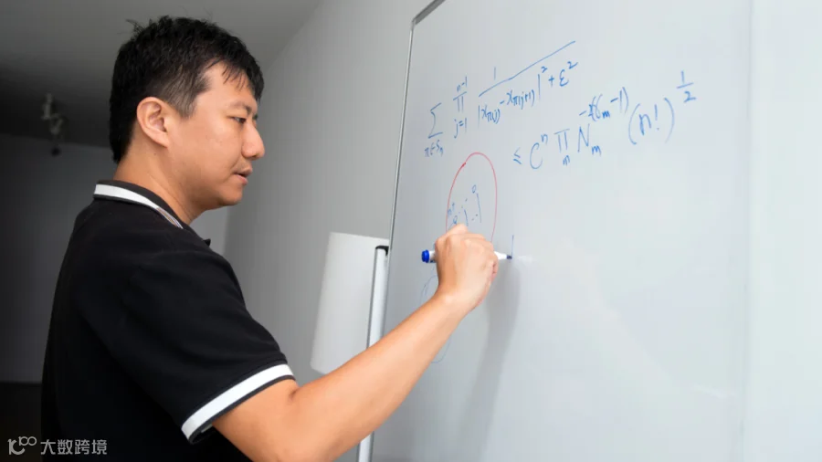 Photo of Prof. Yu Deng writing equations on a whiteboard.