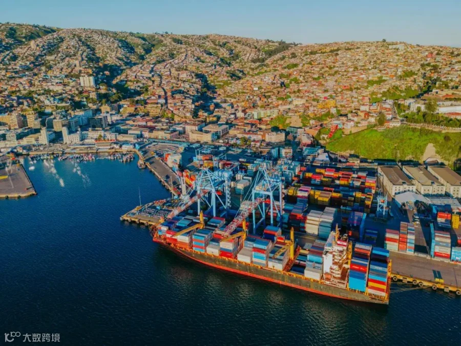 Ship with containers and city on the mountain in the background