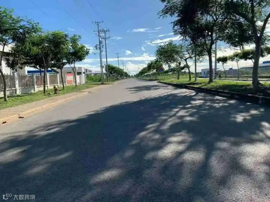 园区内部道路，两侧厂房围墙与绿化完善